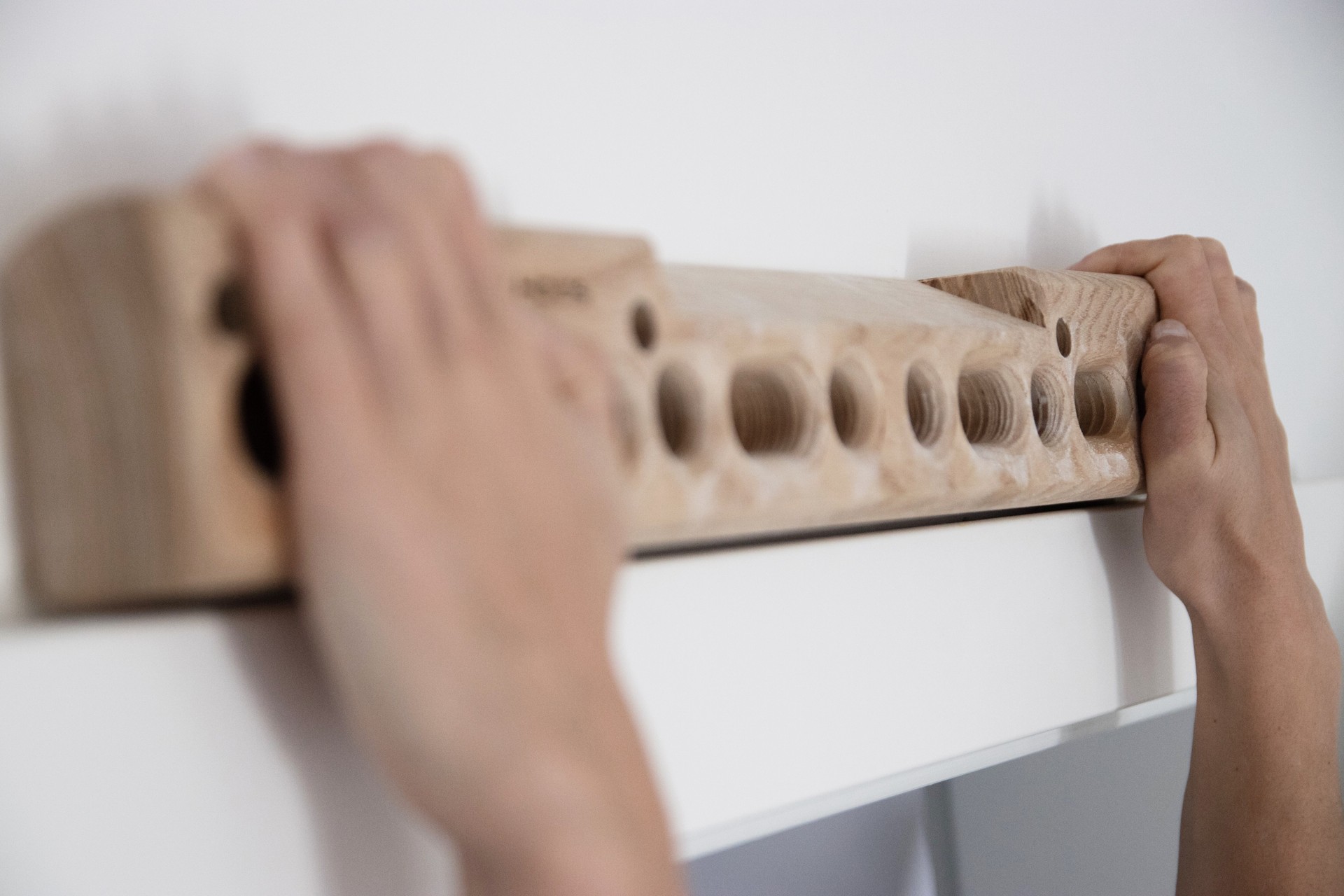 Woman climber training strength on fingerboard at home