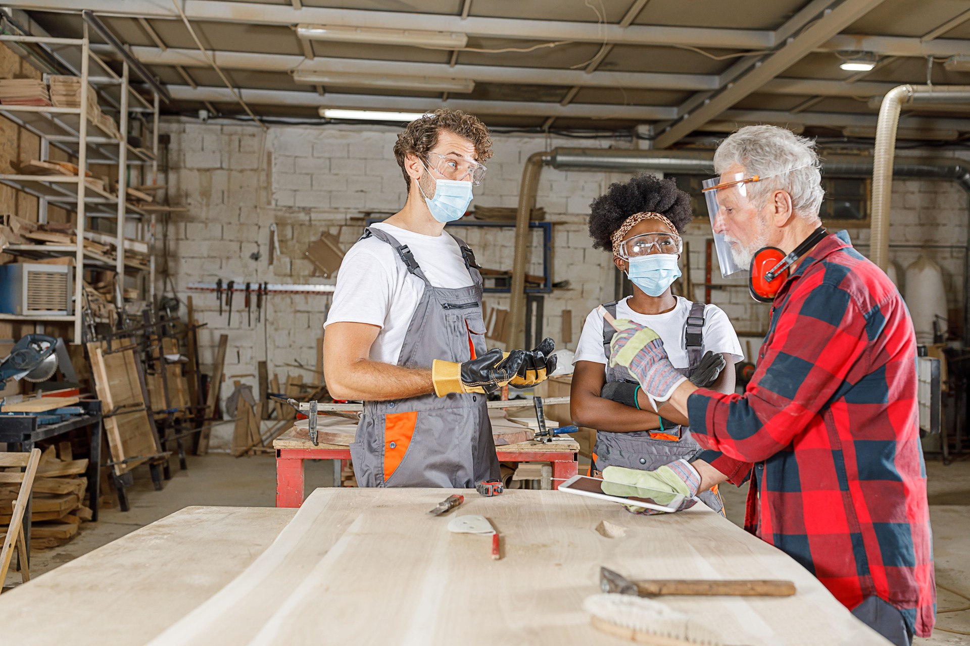 An Experienced Carpenter is Sharing the New Project with His Young Coworkers Over the Laptop During a Pandemic Time.