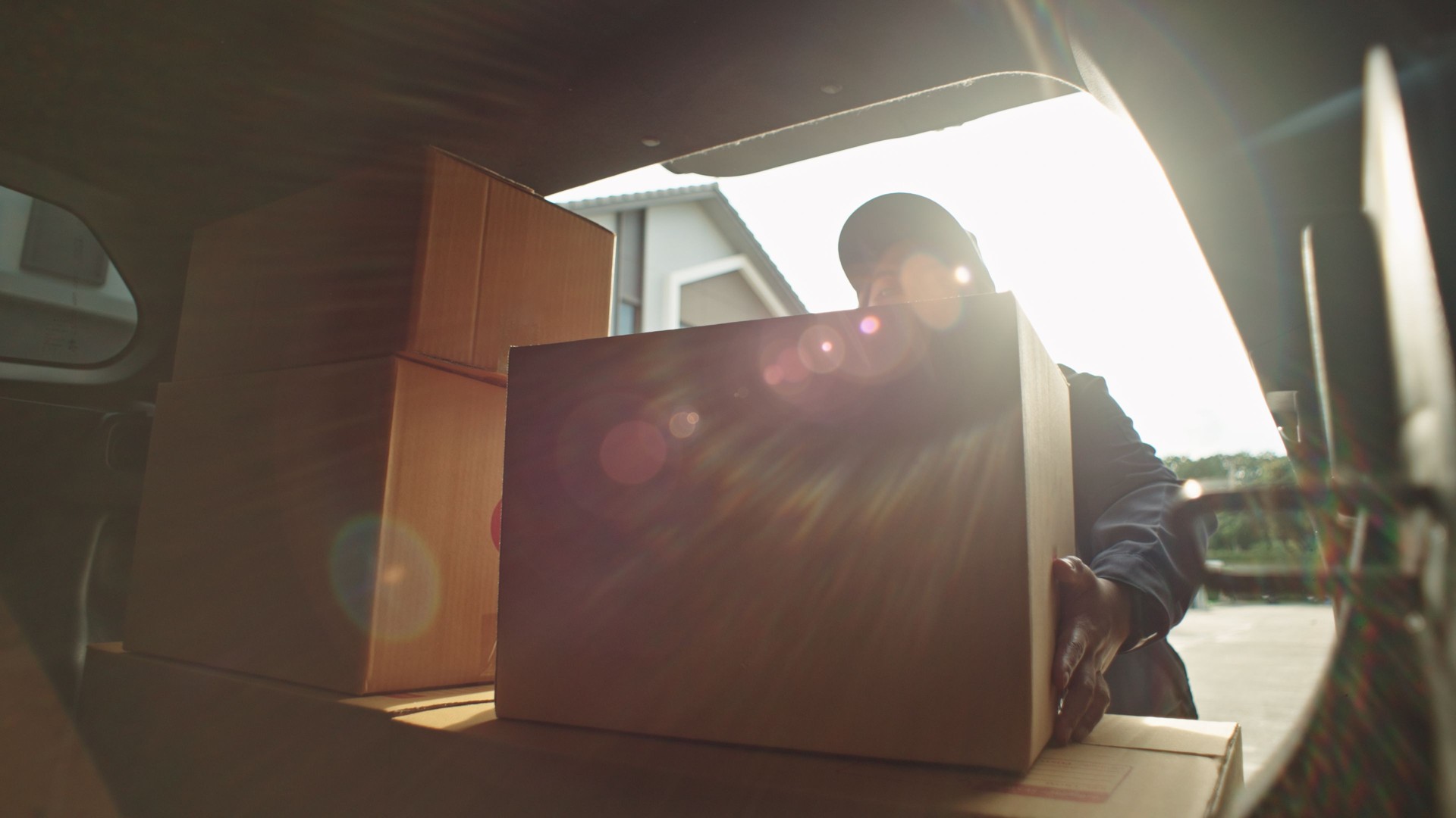 delivery person taking cardboard box from van for delivery.